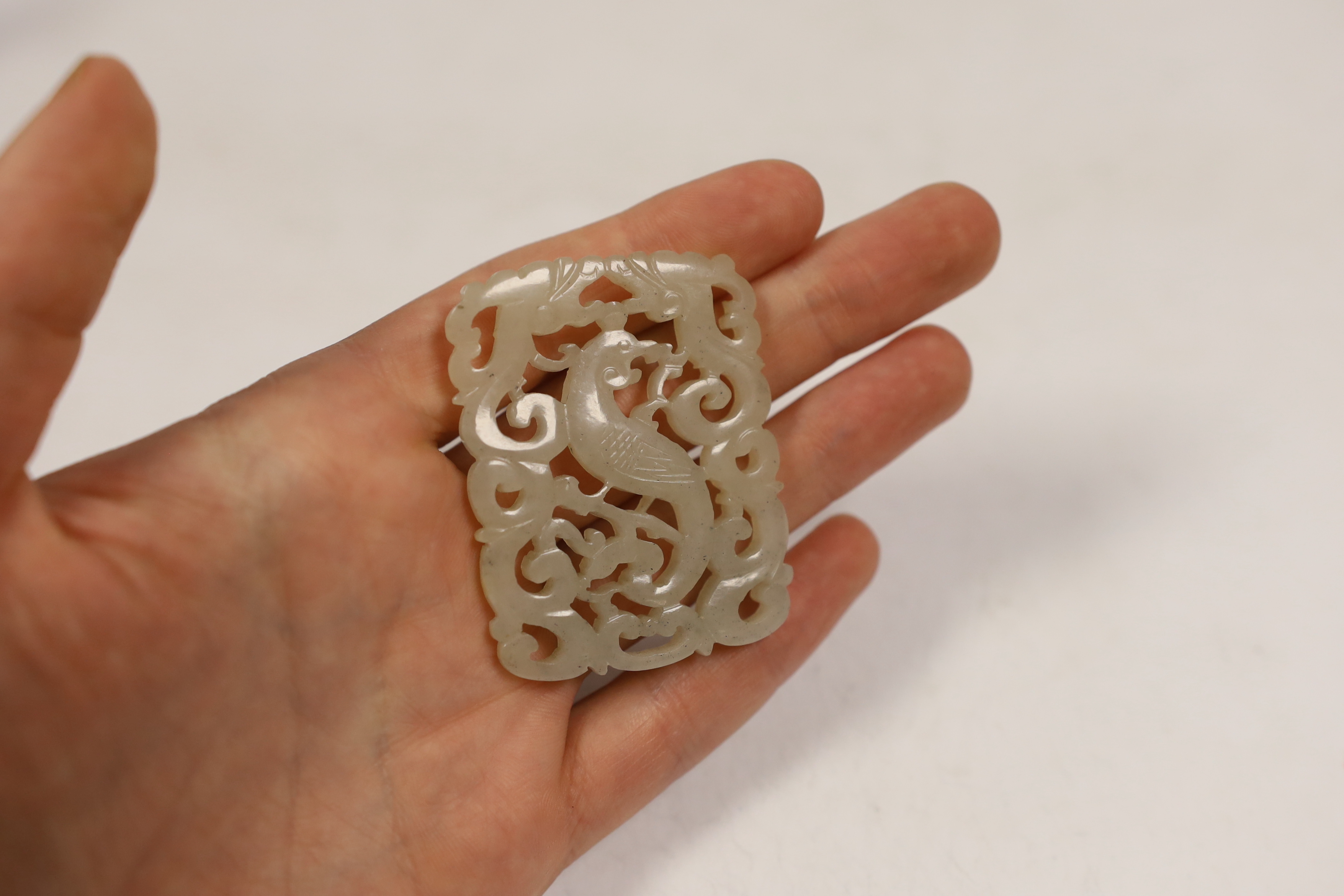 A Chinese jade ‘phoenix’ plaque, late 19th/early 20th century, 5.5 x 4.4cm on hardwood stand